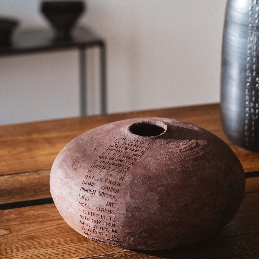 Vase von Marie Martin aus Keramik, rund und bauchig aus rotem Steinzeug Ton mit Schillers Ode "And die Freude" als Relief von oben nach unten verlaufend auf der Vase angebracht.